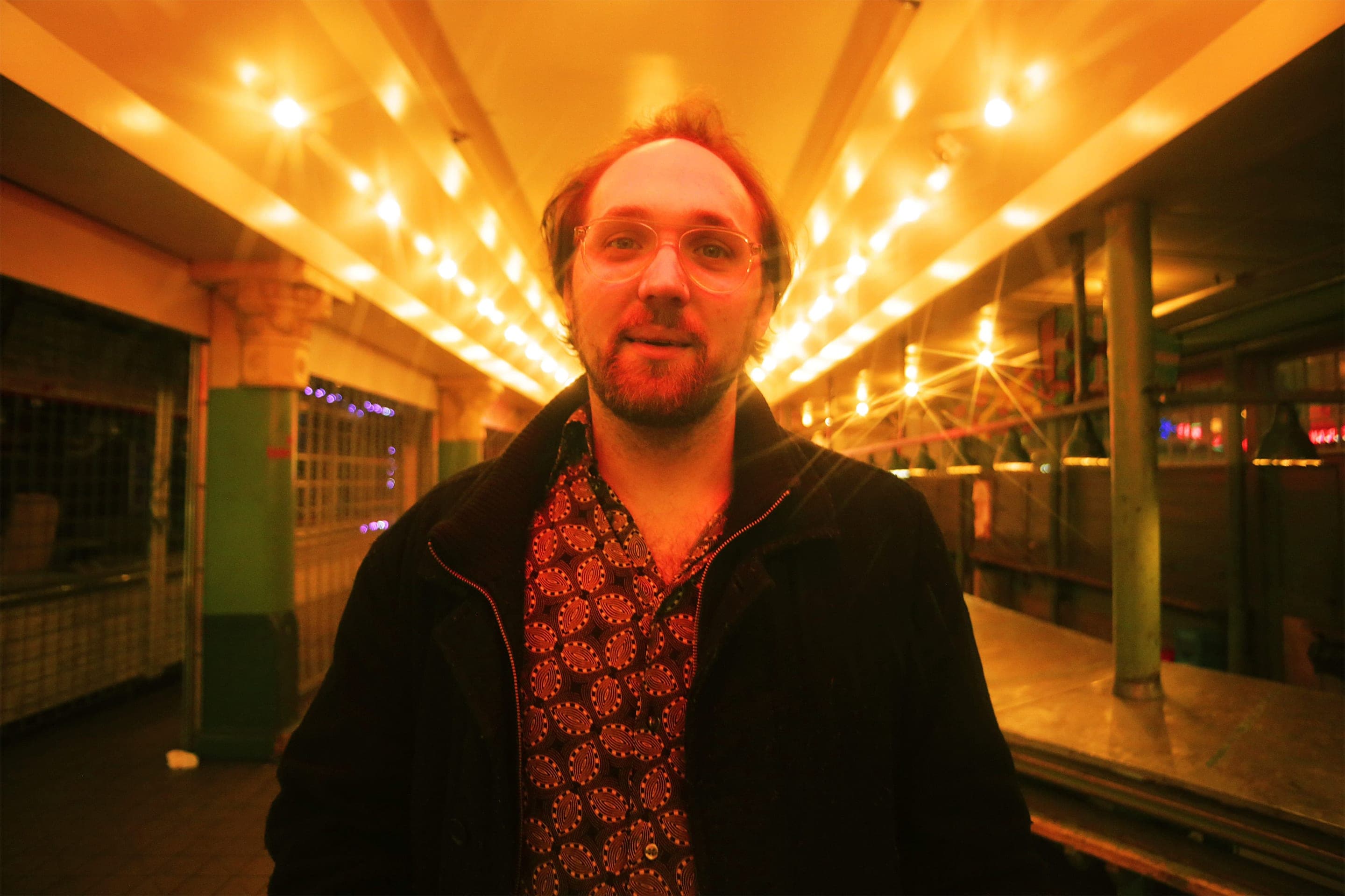 Elliot Preston beneath warm marquee lights at night.